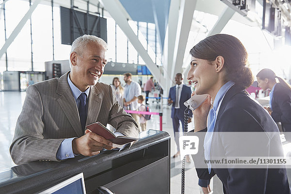 Kundendienstmitarbeiter hilft Geschäftsmann mit Pass am Flughafen-Check-in-Schalter