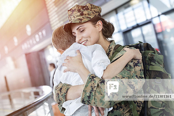 Sohn begrüßt und umarmt Soldatenmama am Flughafen