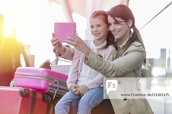 Mutter und Tochter nehmen Selfie mit digitaler Tablettkamera am Flughafen mit.