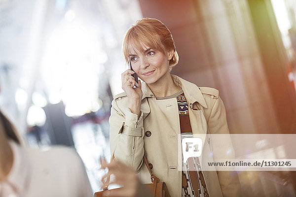 Geschäftsfrau beim Telefonieren am Flughafen