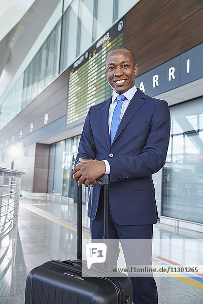 Portrait confident businessman with suitcase in airport concourse