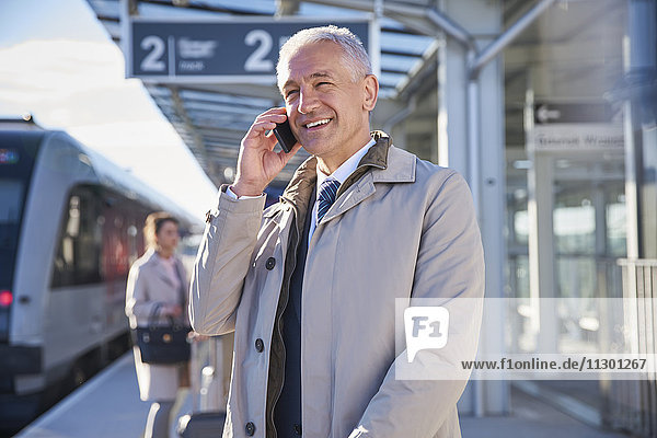 Smiling businessman talking on cell phone outside airport