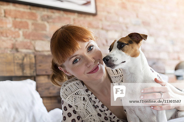 Portrait smiling woman with Jack Russell Terrier dog on bed