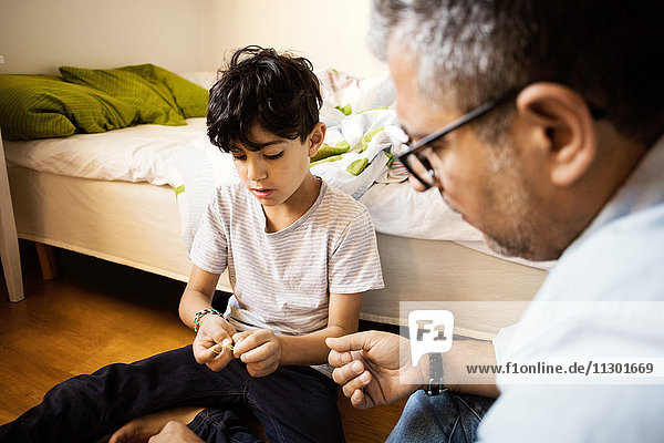 Father and son playing with rubber bands at home