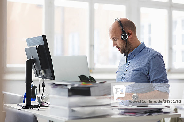 Businessman wearing headphones working at desk in office
