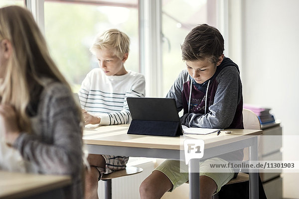 School children e-learning from digital tablet in classroom