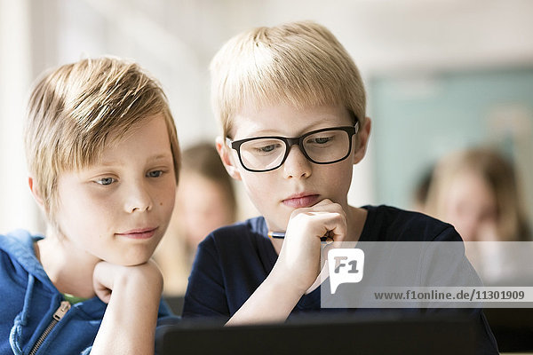 Jungen  die ein digitales Tablett zum Lernen im Klassenzimmer benutzen