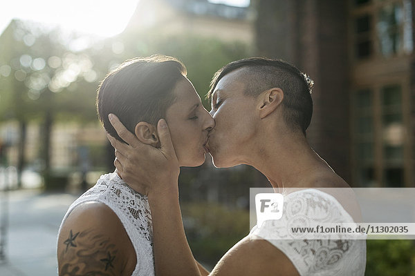 Seitenansicht des frisch verheirateten lesbischen Paares beim Küssen im Freien