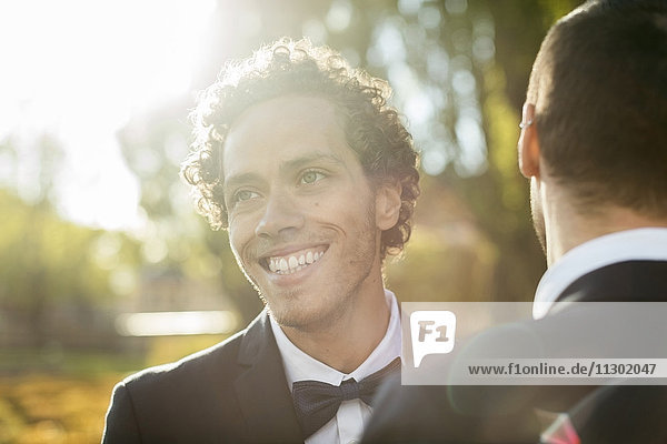 Glücklicher frisch verheirateter schwuler Mann mit Partner an einem sonnigen Tag