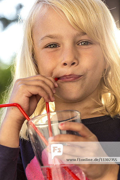 Blond girl drinking with straw from water glass  Kiel  Schleswig-Holstein  Germany  Europe