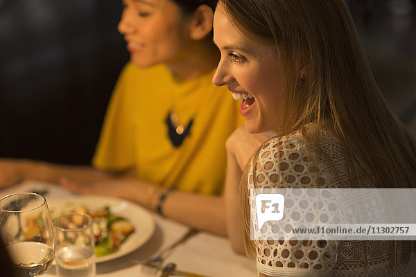 Lächelnde Frau beim Essen mit Freunden am Restauranttisch