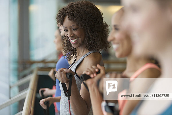 Lächelnde Frauen mit Widerstandsbändern im Fitnessstudio der Übungsklasse