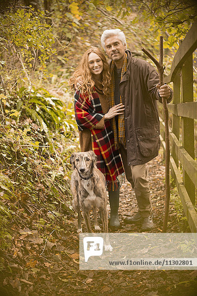 Porträt lächelnd Paar mit Hund und Spazierstock entlang Herbst Zaun
