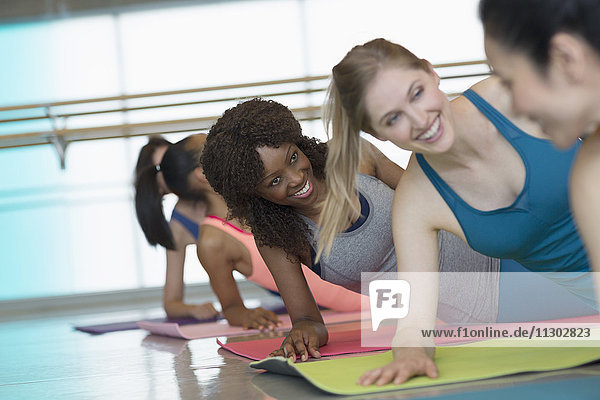 Lächelnde Frauen üben Seitenplanke im Fitnessstudio der Übungsklasse