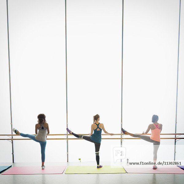 Frauen beim Stretchen der Beine an der Stange im Fitnessstudio der Gymnastikklasse
