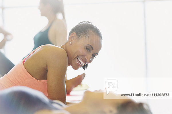 Lächelnde Frauen beim Sprechen und Ausruhen im Fitnessstudio der Übungsklasse