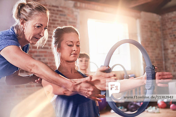 Fitnesstrainerin für junge Frau mit Pilates-Ring im Fitness-Studio