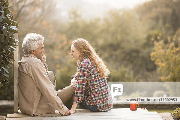 Zärtliches Paar im Gespräch und beim Kaffeetrinken auf der Herbstterrasse
