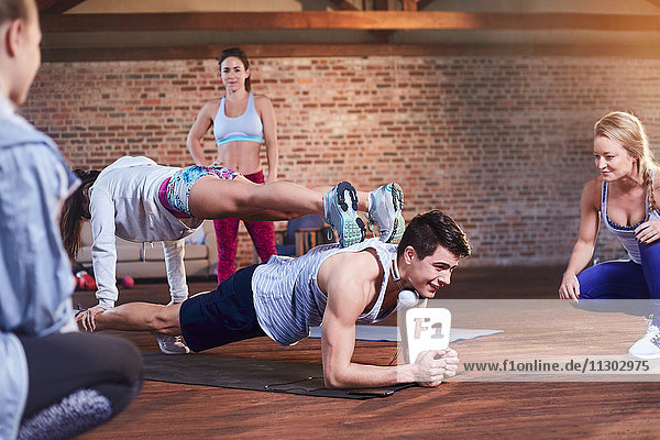 Junger Mann und Frau beim Üben von gestapelten Brettern im Fitnessstudio