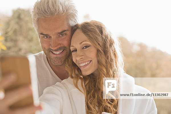 Zärtliches Paar lächelnd unter Selfie mit Kamera-Handy im Freien