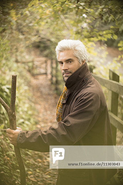 Porträt ernster Mann mit Spazierstock auf Herbstweg