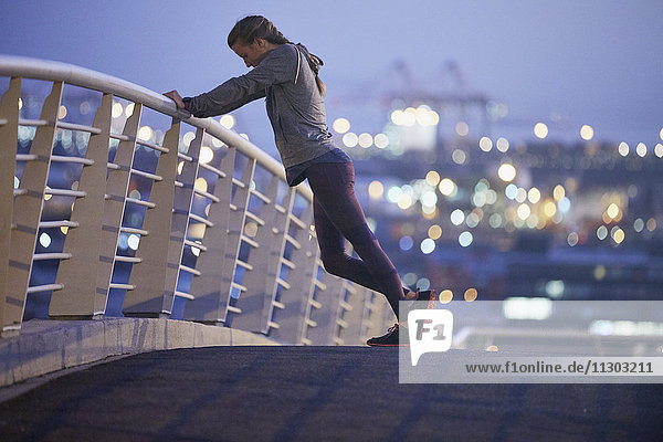 Läuferin  die sich auf einer Fußgängerbrücke in der Morgendämmerung die Beine vertritt