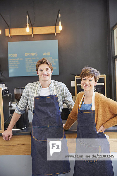 Porträt lächelnde Cafe-Besitzer mit Jeansschürzen im Cafe