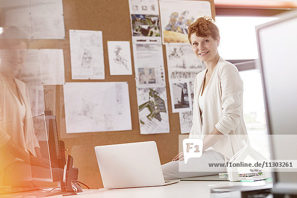 Portrait smiling female designer working at laptop in office