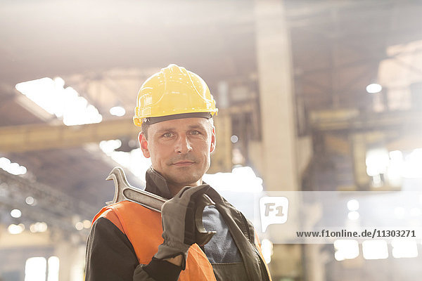 Portrait confident steel worker holding large wrench in factory