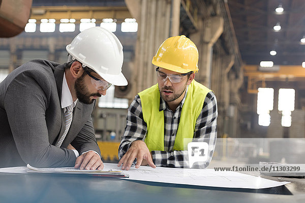 Manager und Ingenieur bei der Überprüfung von Bauplänen im Stahlwerk