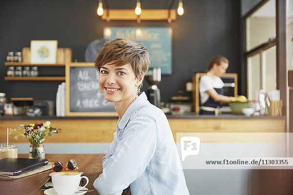 Portrait smiling woman drinking coffee at cafe table