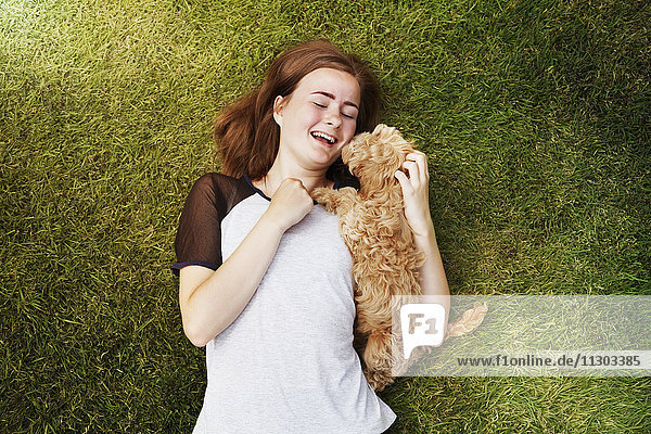 Draufsicht fröhliche junge Frau kuschelnder  liebevoller Hund im Gras
