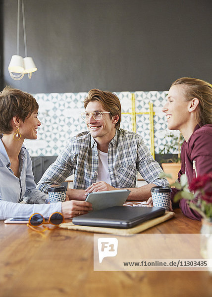 Lächelnde Geschäftsleute  die sich in einem Café treffen und ein digitales Tablet benutzen