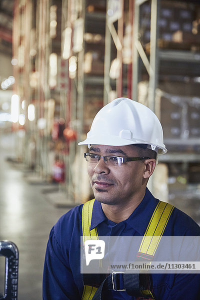 Worker wearing hard-hat looking away in distribution warehouse