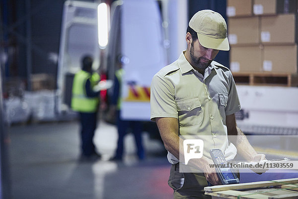 Truck driver worker scanning pallet at distribution warehouse loading dock