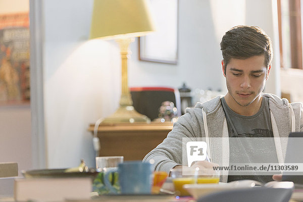 Junger Mann,  Student,  studiert am Frühstückstisch