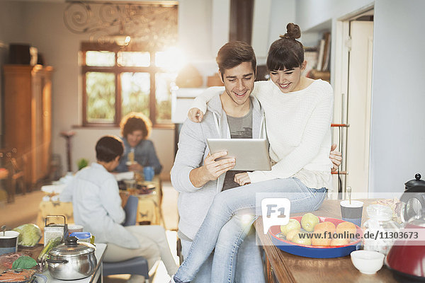 Smiling young couple using digital tablet in kitchen