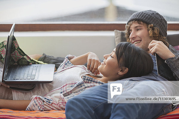 Young couple relaxing laying using laptop