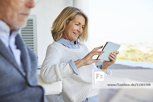 Ältere Frau benutzt digitales Tablet auf der Terrasse