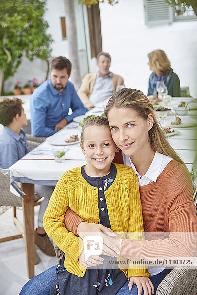 Porträt Mutter und Tochter genießen das Mittagessen im Innenhof mit der Familie