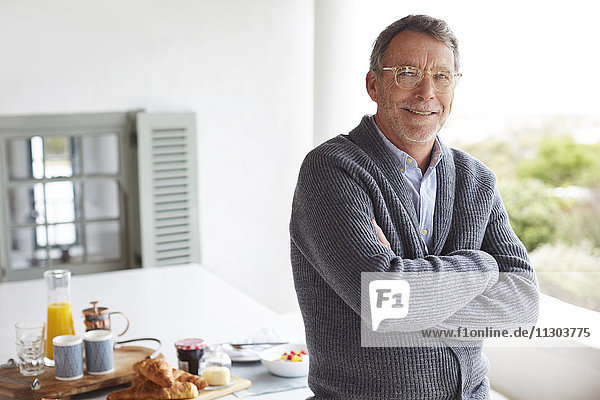 Porträt lächelnder älterer Mann beim Frühstück am Terrassentisch
