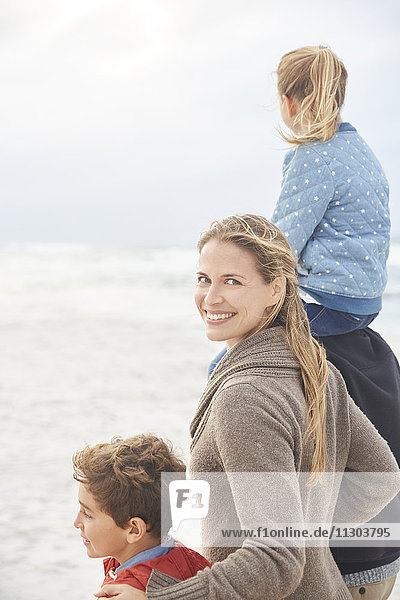 Portrait smiling family walking on winter beach