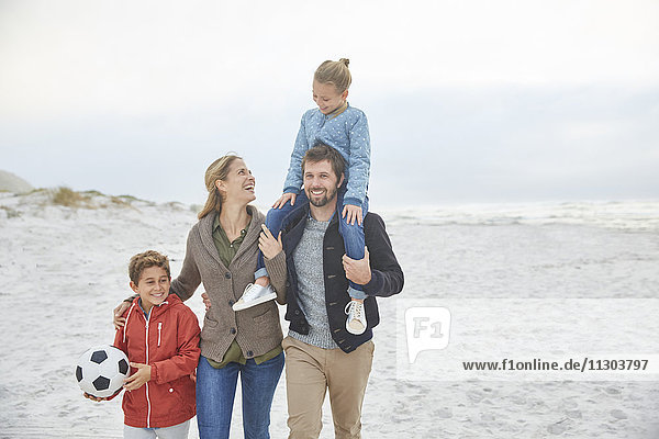 Family with soccer ball walking on winter beach