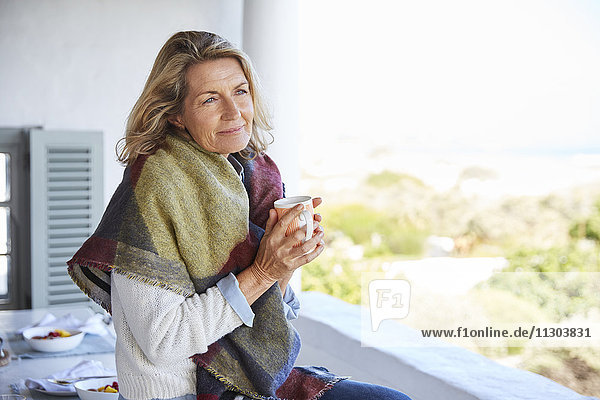 Gelassene Frau trinkt Kaffee auf der Terrasse