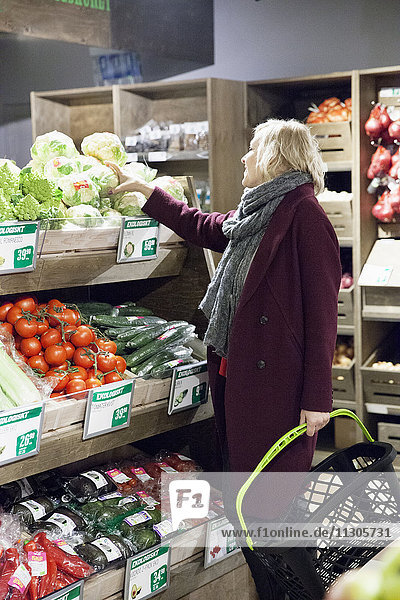 Mittlere erwachsene Frau betrachtet Gemüse im Lebensmittelladen