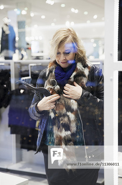 Woman trying on fur scarf in shop