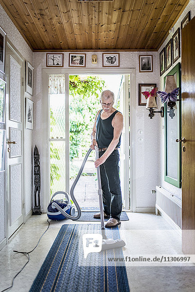 Senior man vacuuming at home