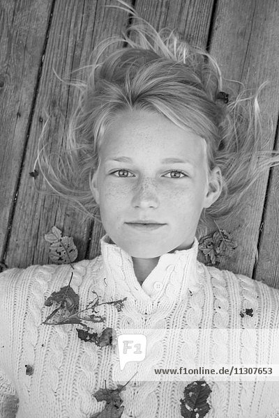 Porträt eines blonden Mädchens auf einem Holzsteg liegend