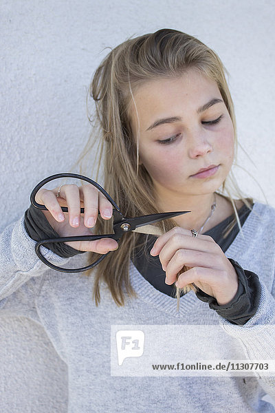 Blond girl cutting her hair