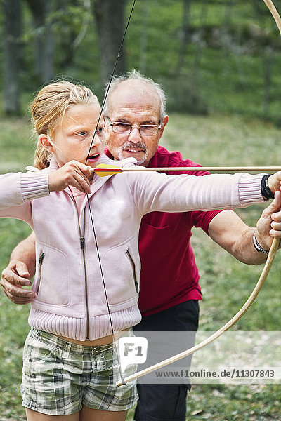 Großvater unterrichtet Enkelin im Bogenschießen
